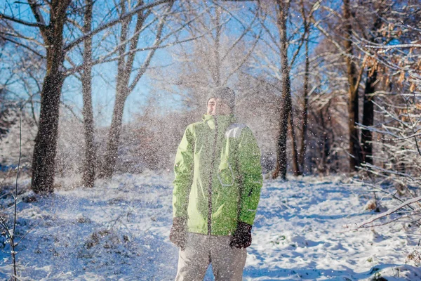 年轻人在冬天的森林里扔雪 这家伙在户外玩得很开心在飘落的雪下感到寒冷的人 冬季活动 — 图库照片