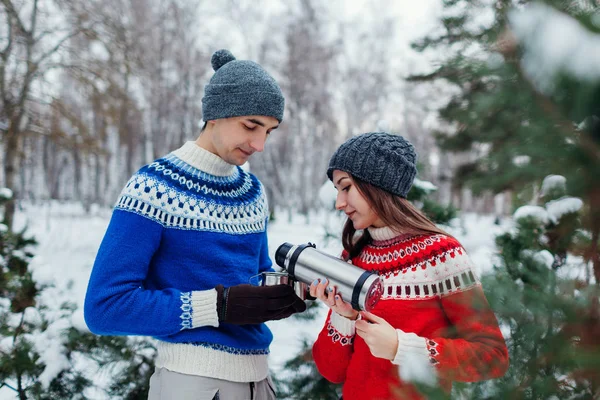 在冬天的森林里 一对年轻夫妇把热水瓶里的热茶倒进杯子里 快乐的人在户外放松假期 — 图库照片