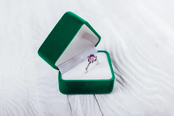 Silver ring with amethyst in green gift box on white wooden background. Present for Valentines day