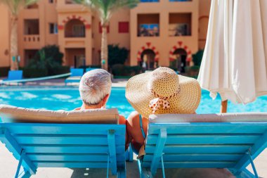 Yüzme Havuzu chaise-şezlong üzerinde yalan tarafından üst düzey iki rahatlatıcı. Tatil zevk insanlar. Sevgililer günü