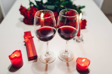 Sevgililer günü şarap, mumlar, kırmızı gül ve hediye kutusu evde ile kutluyor. Romantik bir atmosfer için aşık