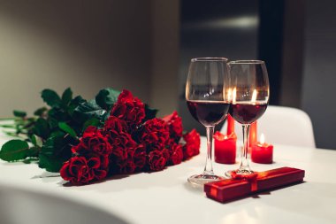 Sevgililer günü şarap, mumlar, kırmızı gül ve hediye kutusu evde ile kutluyor. Romantik bir atmosfer için aşık