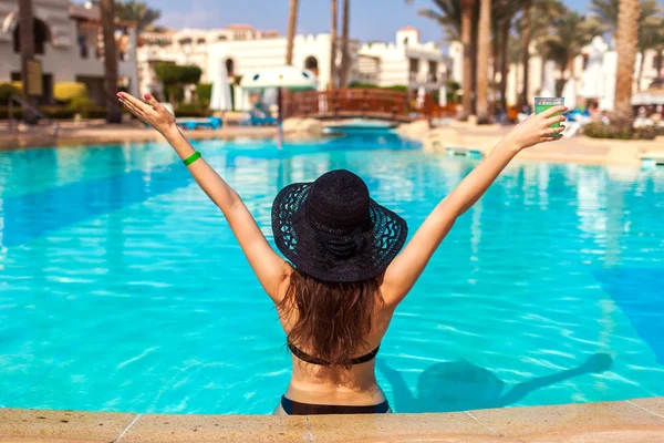 Kadın otel yüzme havuzunda bir kokteyl ile yükseltilmiş silah tutar. Yaz tatili. Herşey dahil konsepti