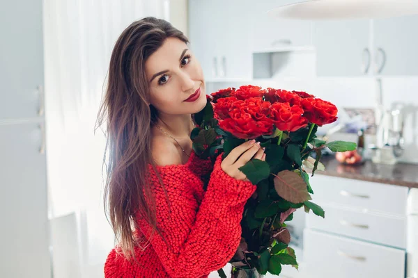 Fiatal nő talált vörös rózsa a konyhában. Boldog lány illatos virágok. Nőnap — Stock Fotó