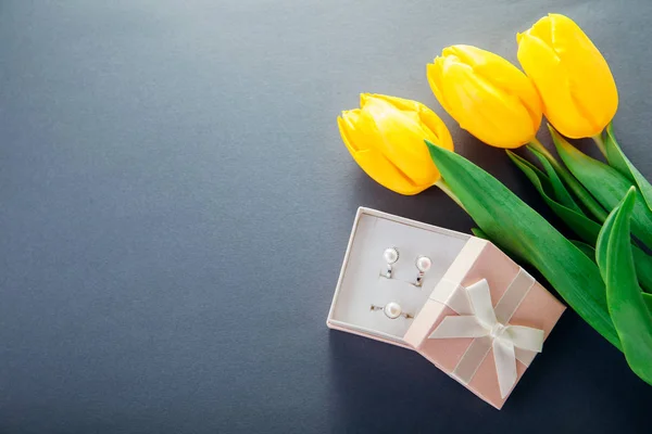 Set zilveren ring en oorbellen met parels in de doos van de gift met gele tulpen. Cadeau voor een Vrouwendag — Stockfoto