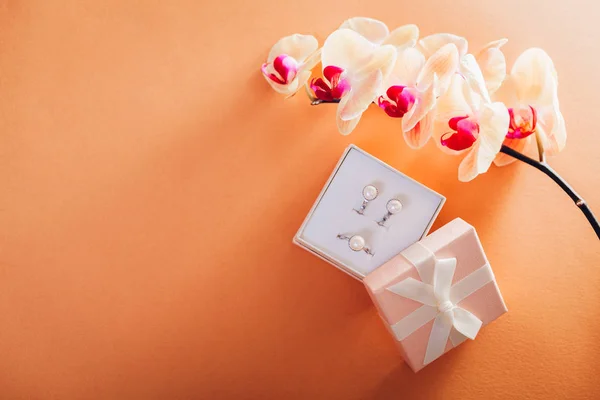 Caja de regalo con un conjunto de joyas de perl rodeado de orquídea. Regalo para el Día de la Mujer — Foto de Stock