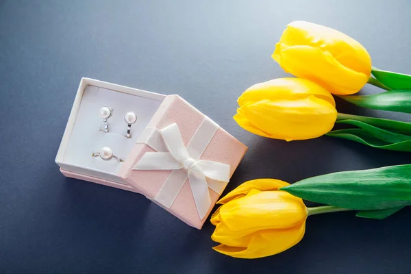Set of silver ring and earrings with pearls in the gift box with yellow tulips. Present for a Women's Day