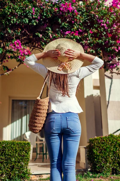 Retrato de mujer joven y elegante caminando bajo flores tropicales por hotel. Vacaciones de verano — Foto de Stock