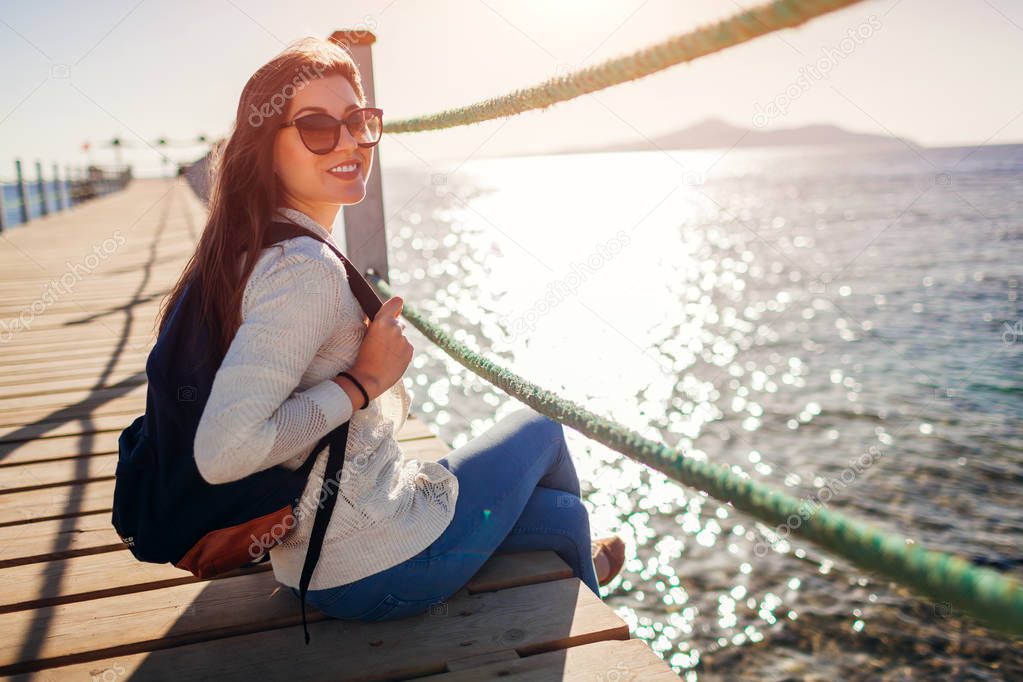 Young female tourist admiring landscape of Red sea and Tiran island on pier. Traveling concept. Summer vacation