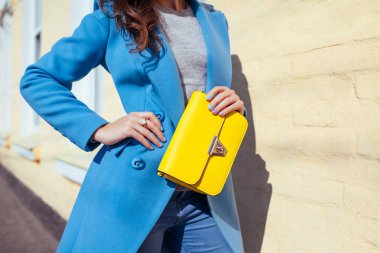 Genç kadın şık çanta tutarak ve trendy mavi ceket giyiyor. Bayan giyim ve Aksesuar bahar. Moda