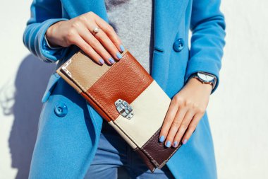 Genç kadın şık çanta tutarak ve trendy mavi ceket giyiyor. Bayan giyim ve Aksesuar bahar. Moda