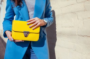Genç kadın şık çanta tutarak ve trendy mavi ceket giyiyor. Bayan giyim ve Aksesuar bahar. Moda