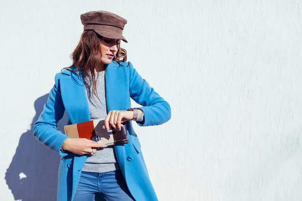 Mujer joven mirando en el reloj, sosteniendo el bolso y vistiendo abrigo azul. Primavera ropa femenina y accesorios. Moda — Foto de Stock