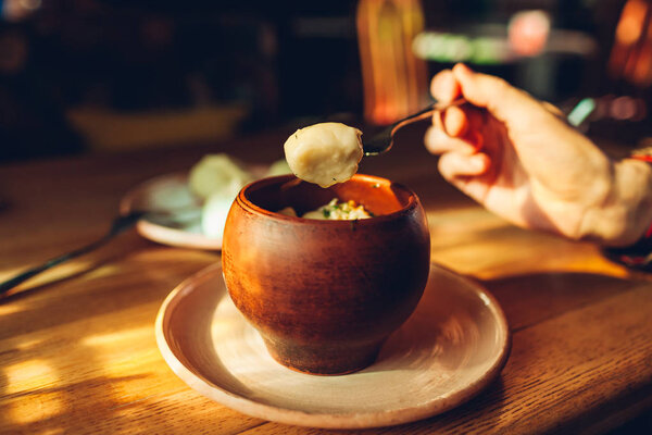Delicious dumplings with chicken and dill in clay pot served in cafe. Ukrainian traditional food