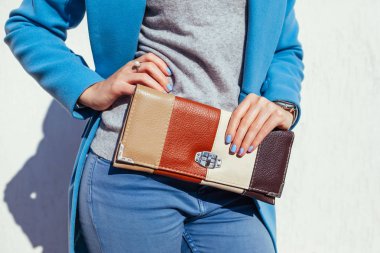 Genç kadın şık çanta tutarak ve trendy mavi ceket giyiyor. Bayan giyim ve Aksesuar bahar. Moda