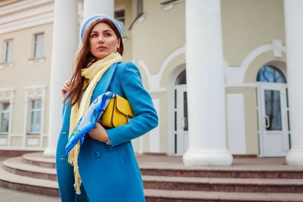 Mujer joven con abrigo azul de moda caminando en la ciudad sosteniendo un bolso con estilo. Primavera ropa femenina y accesorios. Moda — Foto de Stock