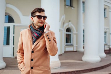 Şehirde Smartphone kullanarak şık delikanlı. Klasik giysi ve aksesuarları giyen yakışıklı adam. Sokak moda