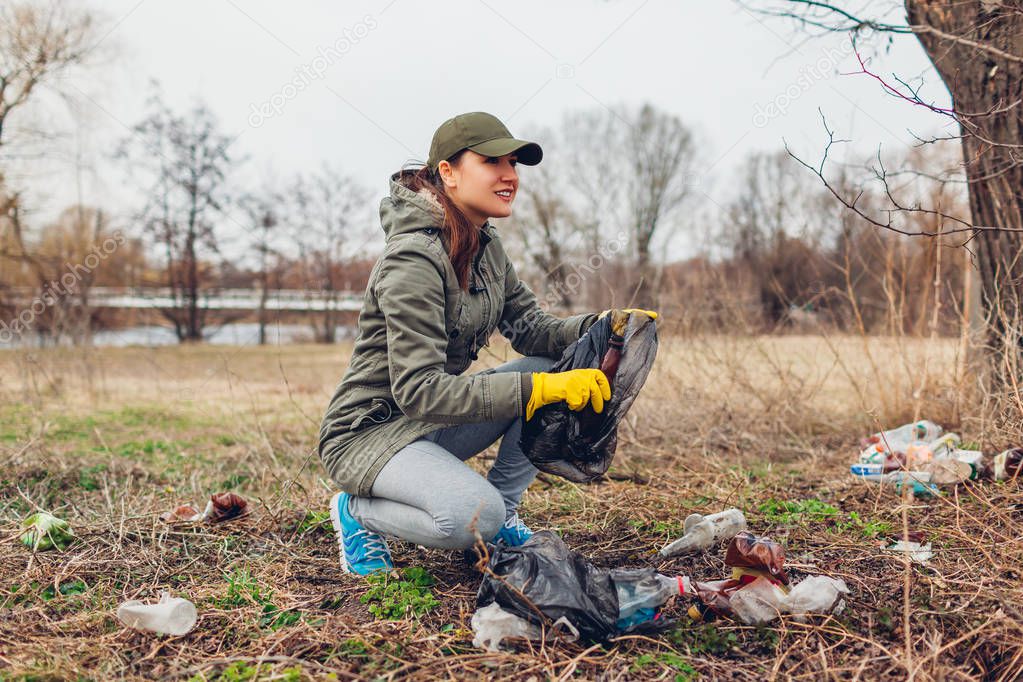 Woman volunteer cleaning up the trash in park. Picking up litter outdoors. Ecology and environment concept
