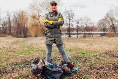 Kadın gönüllü Park'ta çöp temizlenmiş. İnsanlar çöp ve tam çanta ile gösteren sonuç aldım. Ekoloji