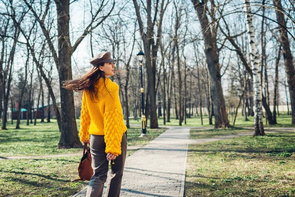 Молодая женщина держит стильную сумочку и носит желтый свитер. Весной женская одежда и аксессуары. Мода — стоковое фото