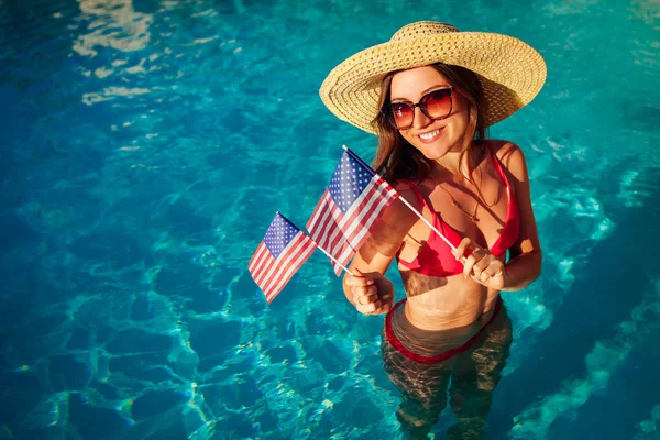 Yüzme havuzunda ABD bayrağı tutan seksi genç kadın. Amerika 'nın bağımsızlık gününü kutluyor