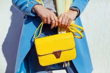 Genç kadın şık çanta tutarak ve trendy mavi ceket giyiyor. Bayan giyim ve Aksesuar bahar. Moda