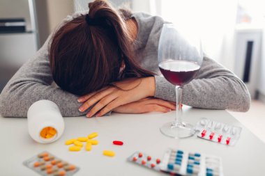 Kadın mutfakta şarap ile hap aldı. İntihar konsepti. Zihinsel bozukluk