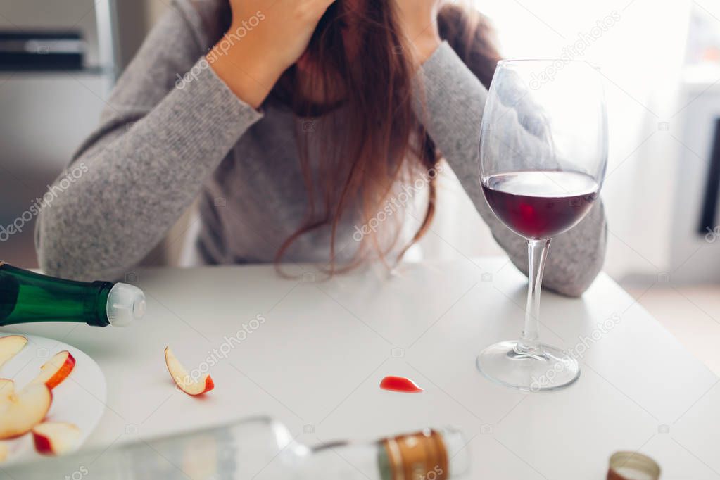 Female alcohol addiction. Young woman woke up on kitchen after party surrounded with wine bottles. Hangover