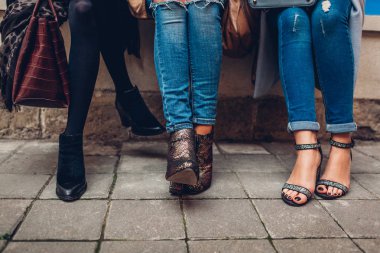 Üç kadın şık ayakkabı ve aksesuarları açık havada giyiyor. Güzellik moda konsepti.