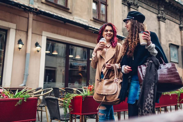 Фотография молодых женщин, идущих по городской улице. и пить кофе. Друзья разговаривают и веселятся — стоковое фото
