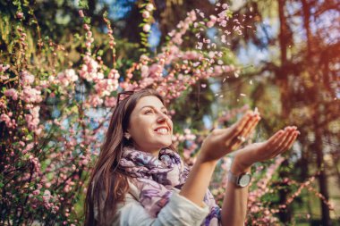 Güzel mutlu kadın çiçek yaprakları bahar bahçesi çiçek lenme zevk atma. Eğleniyor