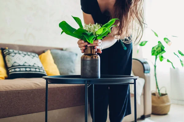 Kobieta kładzie wazon z kwiatami na stole. Gospodyni domowa dbająca o przytulność w mieszkaniu. Wnętrze i wystrój — Zdjęcie stockowe