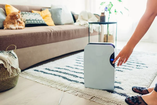 La donna accende il deumidificatore usando il touch panel a casa. Moderno dispositivo di asciugatura per la pulizia dell'aria — Foto Stock