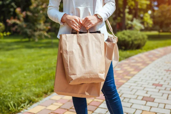 Jeune femme tenant des sacs en papier dans le parc d'été et portant une tenue à la mode . — Photo
