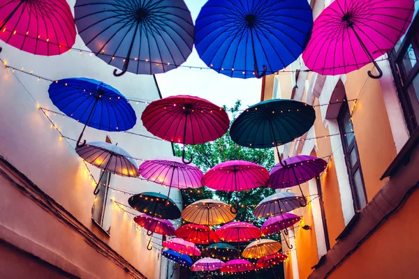 City street decorated with umbrellas and lights. Architecture exterior design in the evening.