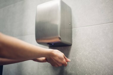 Umumi tuvalette hava kurutucu. Su dolabında elleri kurutmak için kadın.