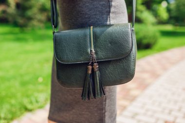 Genç bir kadın şık bir çanta tutuyor ve şık kıyafetler giyiyor. Bahar kadın kıyafetleri ve aksesuarları. Moda.