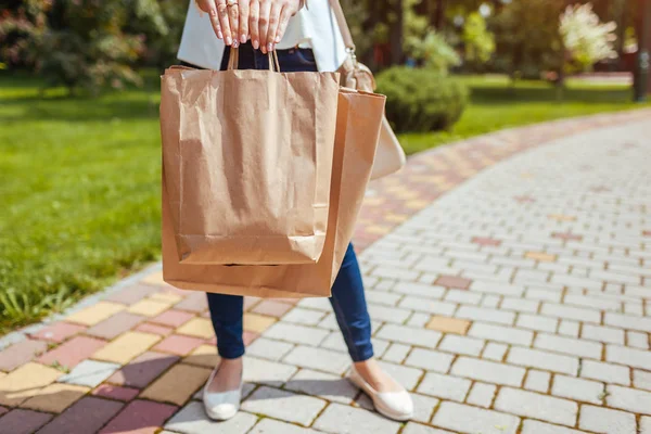 Giovane donna che tiene borse di carta per la spesa nel parco estivo e indossa abiti alla moda . — Foto Stock