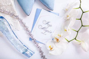 Çiçekler, gelin ayakkabıları ve mücevherlerle çevrili düğün davetiyesi. Gelin sabahı