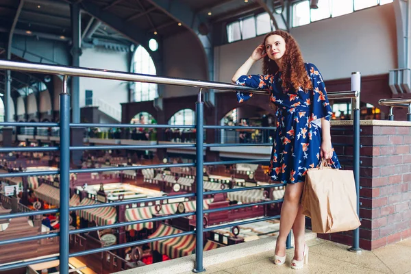 Молода щаслива жінка тримає торговельні паперові мішки в торговому центрі і чекає друзів . — стокове фото