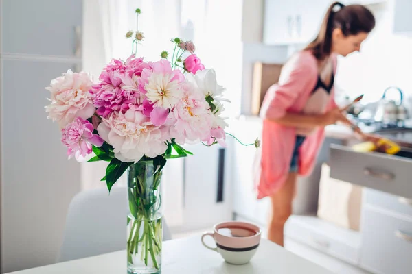 Cocina moderna decorada con peonías rosadas. Ama de casa cocinando la cena. Diseño de interiores . — Foto de Stock