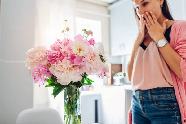 Mujer joven encontró ramo de peonías en la cocina. Feliz chica excitada sonriendo — Foto de Stock