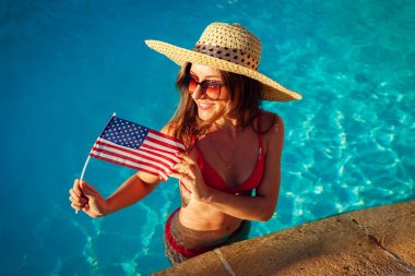 Yüzme havuzunda ABD bayrağı tutan seksi genç kadın. Amerika 'nın bağımsızlık gününü kutluyor