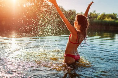 Bikinili genç kadın sudan atlayarak ve sıçrama yapıyor. Yaz tatili