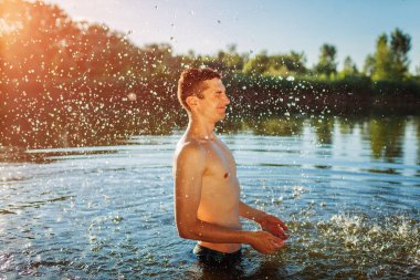 Genç adam suda ve sıçrama yapıyor. Yaz tatili