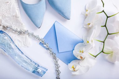 Çiçekler, gelin ayakkabıları ve mücevherlerle çevrili düğün davetiyesi. Gelin sabahı
