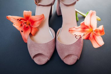 Gri arka planda zambak çiçekleri ile Kadın pembe ayakkabı. Moda