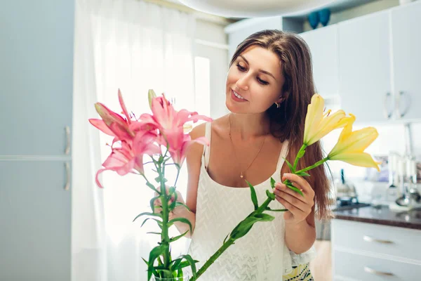 Nő hozza liliomok virágok váza. Háziasszony ügyelve a coziness és dekor a konyhában. Alkotó csokor. — Stock Fotó