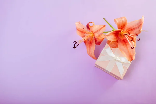 Small gift box with flowers. Jewellery as present with lily on purple background