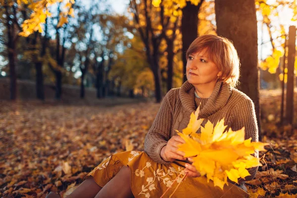 Donna di mezza età che tiene bouquet di foglie d'acero. Signora godendo della natura autunnale e rilassante — Foto Stock